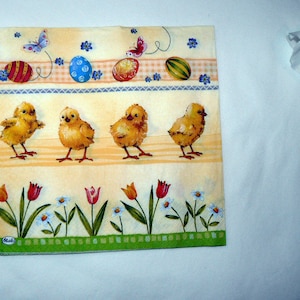 以下が含まれることがあります： 春をテーマにした黄色と白の紙ナプキン。黄色いひよこ、カラフルなイースターエッグ、花で縁取られています。ナプキンには左下に「Maki」のロゴがあります。