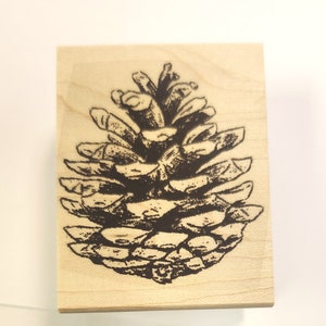 Puede incluir: Un sello de madera con una ilustración en blanco y negro de una piña.