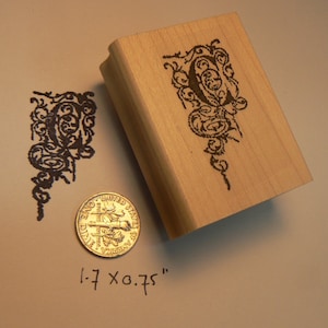 May include: A wooden stamp with a decorative letter "P" design. The stamp is 1.7 x 0.75 inches.