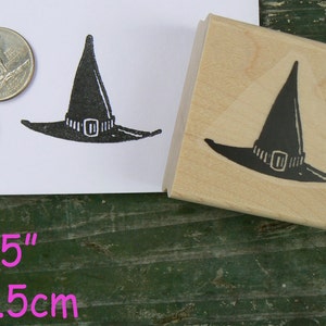 May include: A wooden stamp with a black witch's hat design. The stamp measures 2 x 1.5 inches or 5 x 3.5 cm.