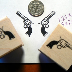 May include: Two wooden blocks with a black and white illustration of a revolver on each. The blocks are 1.25 x 0.75 inches and 3 x 2 cm.