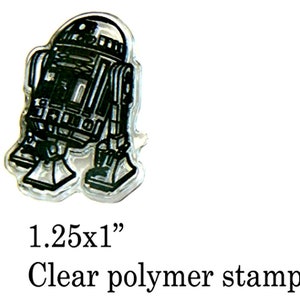 May include: Clear polymer stamp of a black and white R2-D2 robot. The stamp measures 1.25 inches by 1 inch.