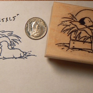 May include: A wooden rubber stamp with a black and white illustration of a baby in a manger with two sheep. The stamp measures 2.75 x 1.5 inches.