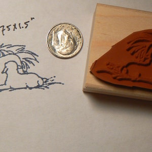 May include: A wooden rubber stamp with a brown rubber image of a nativity scene. The image shows a baby in a manger with a sheep and a star above. The stamp is 2.75 x 1.5 inches.
