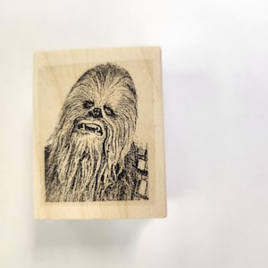 May include: A wooden stamp with a black and white image of Chewbacca from Star Wars.