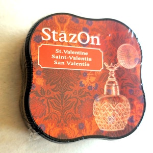 May include: A black ink pad with a red, orange, and purple floral design. The ink pad is labeled "StazOn" and "St. Valentine Saint-Valentin San Valentín".