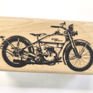 May include: Black and white image of a vintage Harley Davidson motorcycle on a wooden background.