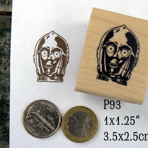 May include: A wooden rubber stamp with a black and white image of C-3PO's head. The stamp measures 1 x 1.25 inches or 3.5 x 2.5 cm. The stamp is labeled "P93".