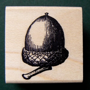 May include: A black and white illustration of an acorn on a wooden background.