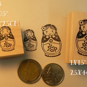 Pode incluir: Três carimbos de madeira com ilustrações em preto e branco de bonecas russas aninhadas. Os carimbos são etiquetados com o texto "P63", "1x0.5" e "1.5x2.5CM", "1x1.5" e "2.5x4CM".