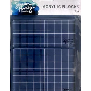 Puede incluir: Dos bloques de acrílico transparentes con un patrón de cuadrícula. Los bloques están empaquetados juntos y etiquetados "Simon Hurley create" y "Ranger Acrylic Blocks 2 pc".