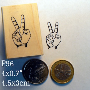 Könnte beinhalten: Ein Holzblock-Stempel mit einem schwarz-weißen Peace-Zeichen-Design. Der Stempel ist 1 Zoll mal 0,7 Zoll groß, oder 1,5 cm mal 3 cm.