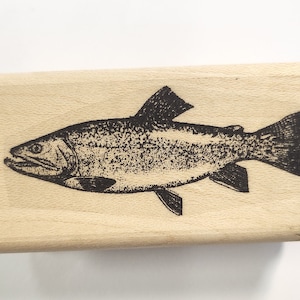 May include: A wooden rubber stamp with a black and white illustration of a trout fish.