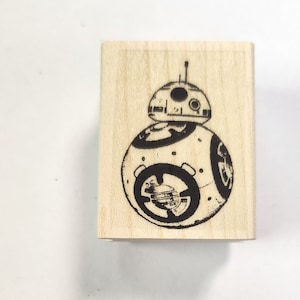 Könnte beinhalten: Ein Holzstempel mit einem Schwarzweißbild eines Star Wars BB-8 Droiden.