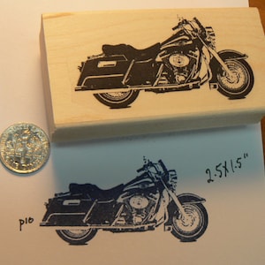 May include: A black and white rubber stamp of a motorcycle with the text "2.5x1.5" printed on the side. The stamp is mounted on a wooden block.