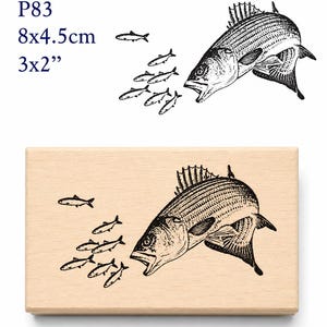 May include: A wooden stamp featuring a detailed illustration of a large fish with its mouth open, chasing a school of smaller fish. The stamp measures 3x2 inches and includes the text "P83".