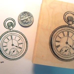 May include: A black and white illustration of a pocket watch with roman numerals on a wooden block. The block is labelled "P8 2x1.5" 5x3.5cm.