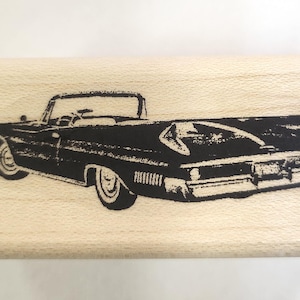 May include: A black and white image of a vintage convertible car with the top down. The car is facing to the right and has a long, sleek design.