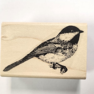 Puede incluir: Un sello de madera en blanco y negro con una ilustración detallada de un pájaro con cabeza negra y cuerpo blanco.