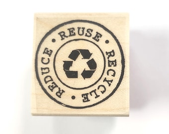 Könnte beinhalten: Holzstempel mit einem runden Design mit den Worten "Reduzieren, Wiederverwenden, Recyceln" und einem Recycling-Symbol.