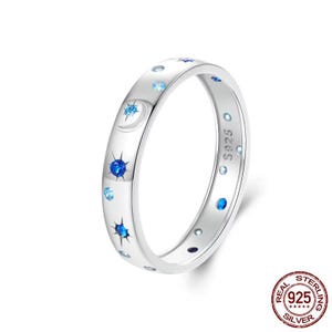 Peut inclure: Une bague en argent avec un motif de croissant de lune et d'étoiles. La bague est sertie de pierres précieuses bleues et blanches. La bague est estampillée "S925" et "REAL STERLING SILVER 925".