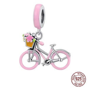 Puede incluir: Un charm de plata en forma de bicicleta rosa con una cesta de flores. El charm tiene un acabado de esmalte rosa y está diseñado para ser usado en una pulsera de charms.