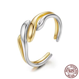 May include: A silver and gold adjustable ring with a twisted design. The ring is made of real sterling silver.
