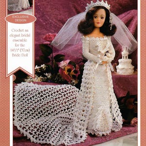 May include: A crochet bridal ensemble for a 14.5-inch doll. The doll wears a white, off-the-shoulder wedding dress with long sleeves, a veil, and a crown. A matching crocheted shawl and a small cake are also visible.