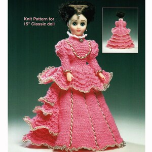 May include: A pink knitted dress for a 15-inch classic doll. The dress features a layered skirt, puffed sleeves, and gold trim. The doll has black hair and blue eyes. The text on the image reads "Knit Pattern for 15" Classic doll."