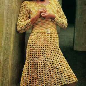 May include: A vintage crochet dress in shades of yellow, orange, and brown. The dress features a long-sleeved top with a square neckline and a fitted skirt, cinched at the waist with a belt. The open weave design adds a delicate texture to the garment.