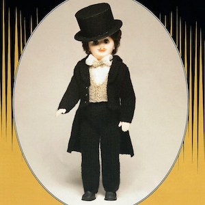 May include: A vintage doll dressed in a black suit, top hat, and bow tie. The doll has a painted mustache and is wearing a knitted vest. The doll is standing in front of an oval frame with a gold and black design.