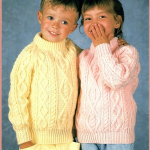 Peut inclure: Deux enfants portant des pulls en tricot torsadé assortis. Le garçon porte un pull jaune et la fille porte un pull rose.