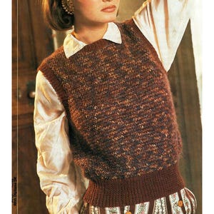 May include: A brown and tan knitted vest with a ribbed hem and neckline. The vest is worn over a white collared shirt. The knitted vest has a textured appearance and is a classic style.