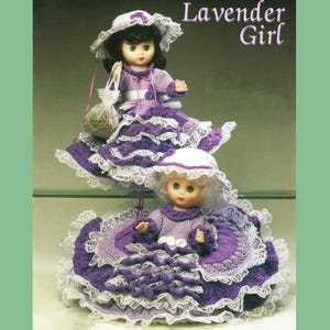 May include: Two crocheted dolls dressed in lavender and white dresses with lace trim. The dolls are wearing hats and have painted faces. The dolls are titled "Lavender Girl".