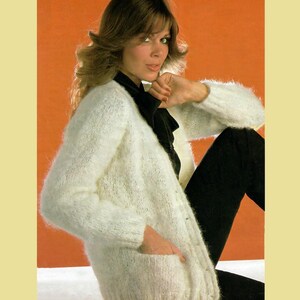 May include: A white fuzzy cardigan with a button closure and pockets. The cardigan is made of a soft, fluffy yarn.