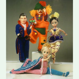 May include: Four knitted dolls dressed in different costumes. A clown doll with orange overalls, a doll in a blue suit, a ballerina doll in a purple tutu, and a ballerina doll in a pink and blue dress.