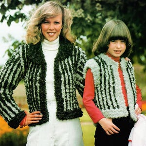 May include: Two people wearing matching green and black striped jackets and vests. The jackets have a fuzzy texture and a dark green collar. The vest is sleeveless and has a similar striped pattern. The person on the left is wearing a white turtleneck and white trousers.