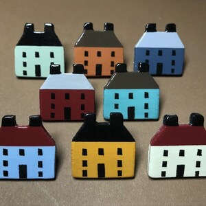 May include: Set of ten miniature painted houses in various colors, including red, blue, yellow, green, and brown. Each house has a white door and windows.