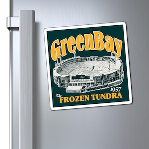 May include: A square magnet with a dark green background and a vintage illustration of a stadium. The text "Green Bay" is in yellow, with "The Frozen Tundra 1957" below the stadium image.