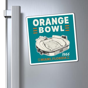 May include: A square magnet featuring a teal background with the white text ORANGE BOWL and orange horizontal lines. It displays a detailed illustration of the Miami Orange Bowl stadium, the year 1966, and the text MIAMI, FLORIDA in orange.