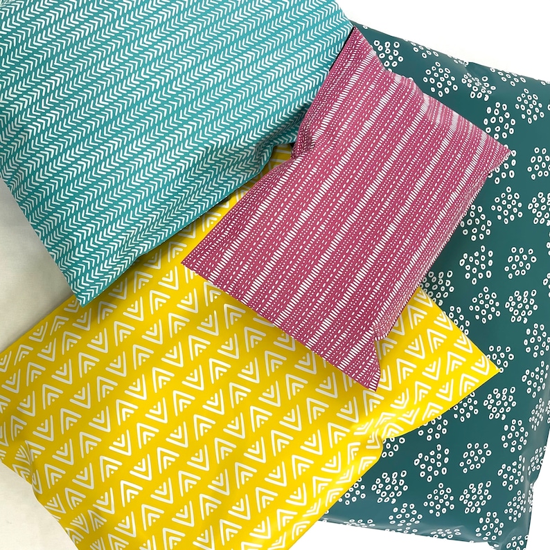 May include: Four fabric swatches with different geometric patterns. The swatches are teal with white chevron, pink with white stripes, yellow with white zigzags, and teal with white polka dots.
