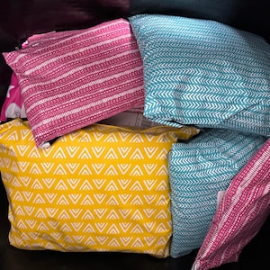 May include: A collection of five patterned pillowcases in a black tote bag. The pillowcases are in various colours and patterns, including yellow with white triangles, teal with white chevron, and pink with white stripes.