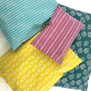 May include: Four fabric swatches with different geometric patterns. The swatches are teal with white chevron, pink with white stripes, yellow with white zigzags, and teal with white polka dots.