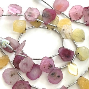 May include: A strand of pink and yellow gemstone beads strung on silver wire. The beads are faceted and have a natural, irregular shape.