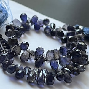 May include: A strand of dark blue gemstone beads in a teardrop shape.