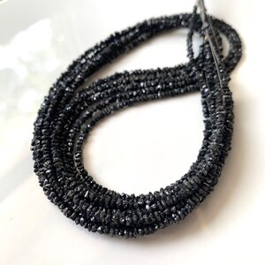 May include: A strand of black diamond beads. The beads are rough and have a natural, unpolished look.