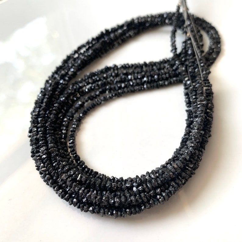 May include: A strand of black diamond beads. The beads are rough and have a natural, unpolished look.