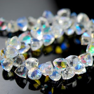 May include: A strand of iridescent clear quartz gemstone beads. The beads are faceted and have a teardrop shape.