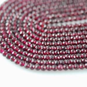 May include: A strand of deep red faceted garnet beads. The beads are round and have a smooth, polished finish.