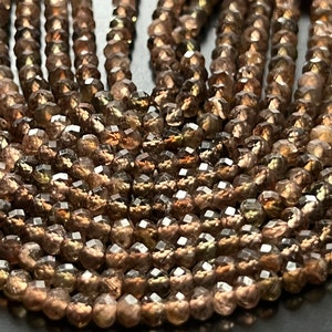 May include: A strand of faceted brown gemstone beads. The beads are round and have a shiny, iridescent finish.
